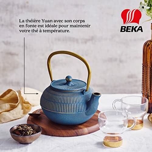 Théière bleue en fonte avec tasses transparentes.