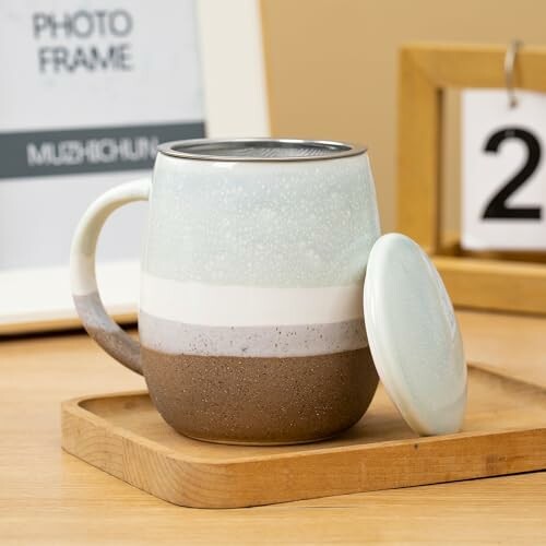 Tasse en céramique avec couvercle sur un plateau en bois.