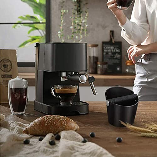 Machine à café moderne sur un comptoir de cuisine avec un verre de café et un pain.