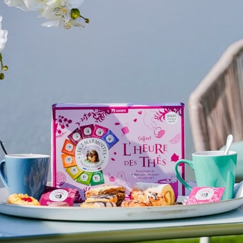 Coffret de thé avec tasses et pâtisseries sur une table extérieure.