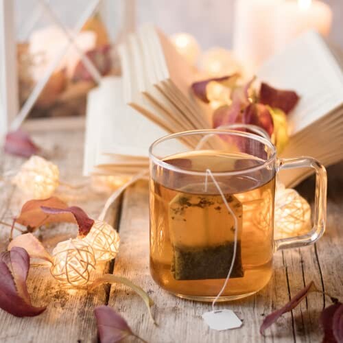 Tasse de thé avec un livre et des lumières d'ambiance.