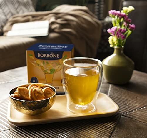 Tasse de thé avec des biscuits et une boîte de thé Borbone sur une table.