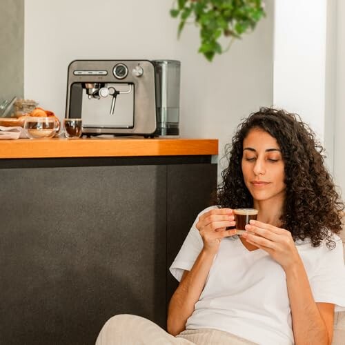 Femme buvant du café près d'une machine à expresso.